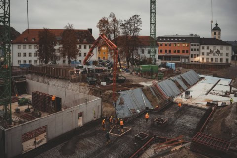 Construction site with foundation work and heavy machinery during building development, focusing on reinforced concrete and structural engineering.