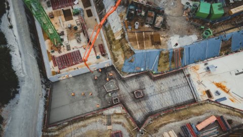 Constructing building foundation with concrete and steel reinforcement at construction site.