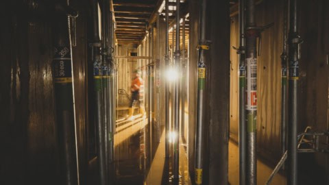 Scaffolding and structural framework in a building under construction, showcasing steel pipes and wooden walls