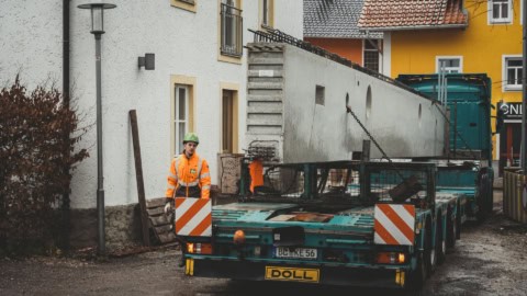 Construction worker in safety vest and helmet near transportation equipment