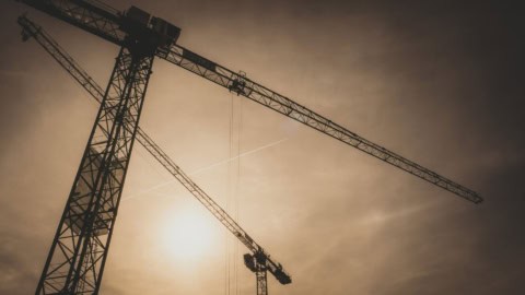Tower cranes at construction site during sunset, highlighting industrial staging and Mahu code implementation for optimal project staging.