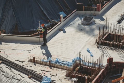 Concrete construction site with steel rebar reinforcement and a worker inspecting the area, showcasing staging for high-rise building development.