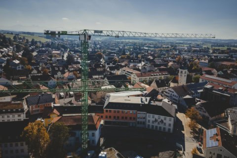 Crane lifting equipment installing in a charming residential town for construction project, showcasing urban development and infrastructure expansion under clear blue sky.
