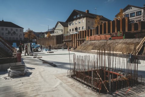 Pre-construction site with foundation work and rebar structure in urban residential area, emphasizing construction progress