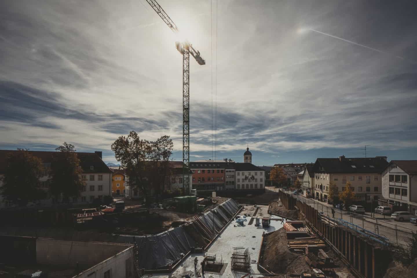Construction site with a tower crane and partially built infrastructure in a residential area under a cloudy sky, showcasing modern urban development and structural staging processes.