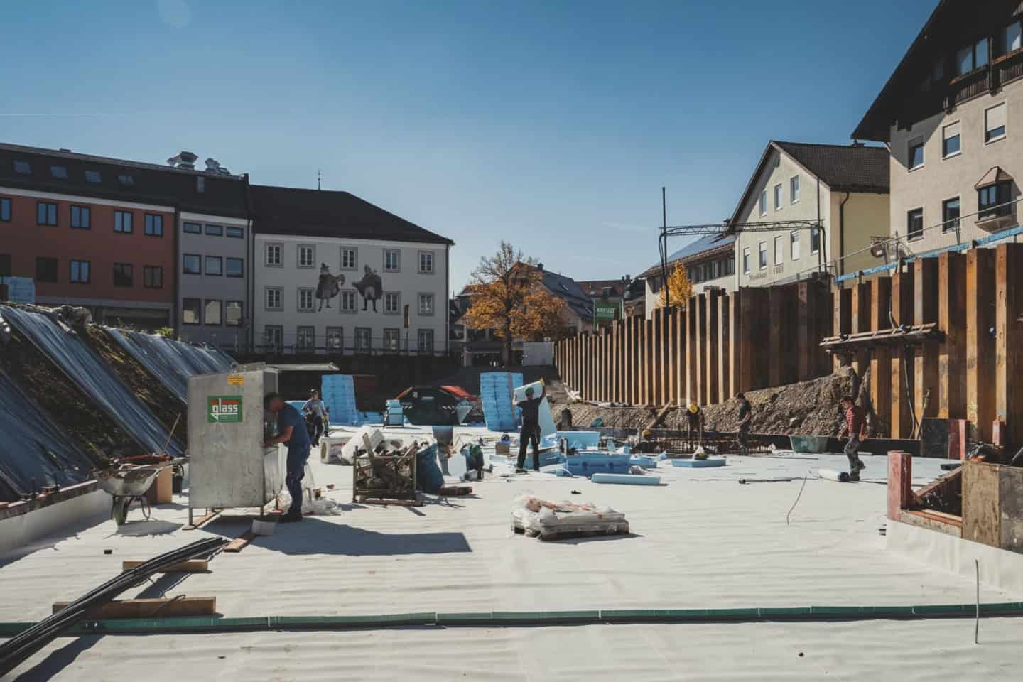 Concrete roof laying in progress at a construction site with workers, building materials, and scaffolding in a European town