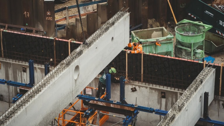 Welding workers assembling concrete structures at a construction site with safety gear and reinforcement bars.